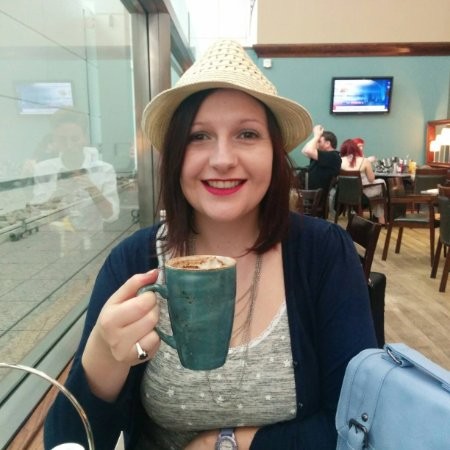 An image of Linsey Wilson - freelance graphic designer holding a coffee and smiling.